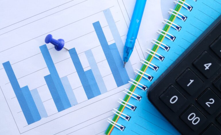 financial graph, calculator and notepad on table